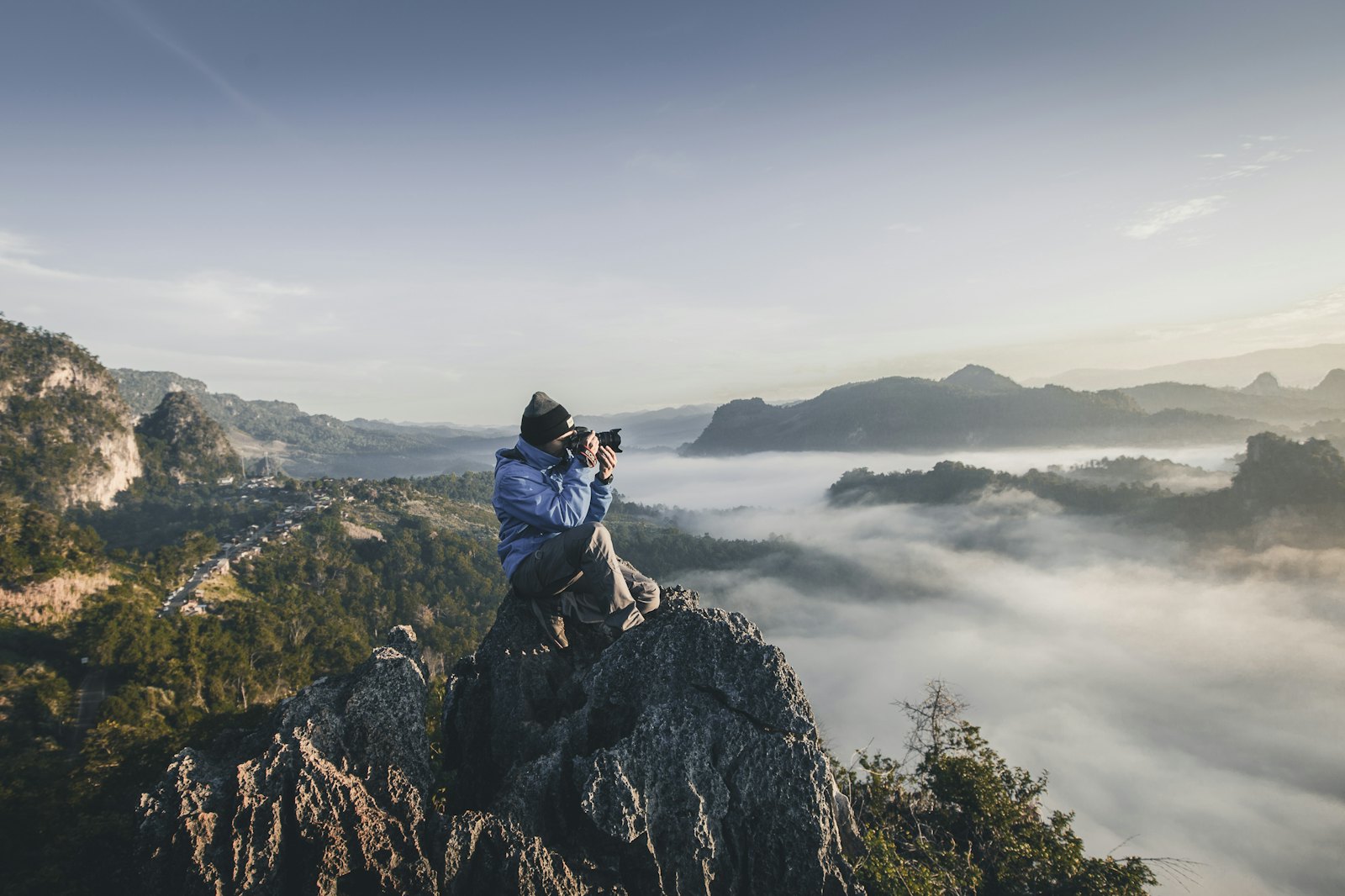 A photographer on a mountain above the clouds